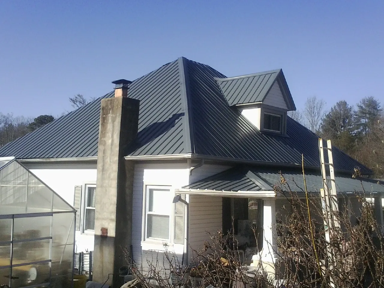 Dark blue standing seam metal roof on a white farmhouse with dormer — Slate & Tile Roof Repair by Roofing Brothers in Baileyton