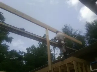 Carpenter setting a ridge beam over a new addition frame — Ice Dam Removal by Roofing Brothers in Baileyton