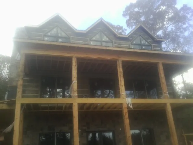 Dormers and porch framing on a large log home under construction — Roof Coating work by our crew in Baileyton
