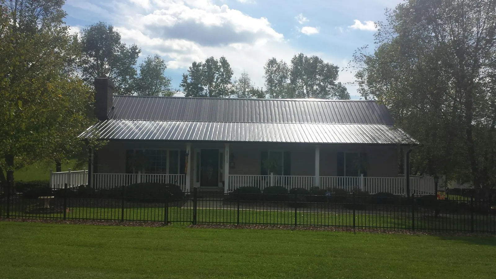 Gray metal roof on a brick ranch with a full width front porch — Gutter Guard Installation work by our crew in Baileyton
