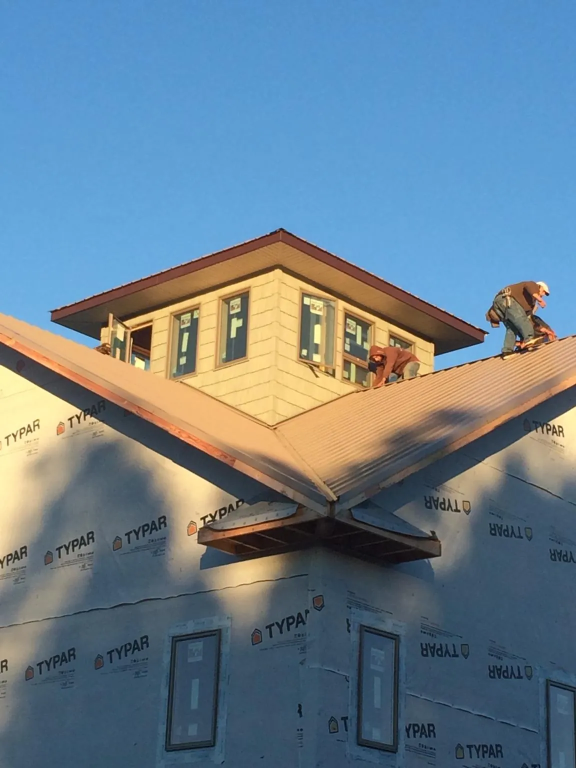 Roofers working around a rooftop cupola on a new metal roof at sunset — Roof Waterproofing in Baileyton by Roofing Brothers